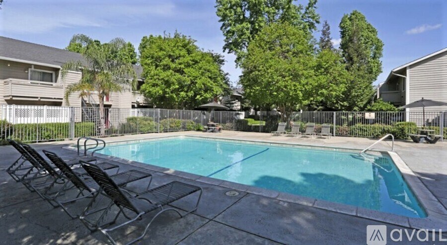 A pool surrounded by trees and chairs.