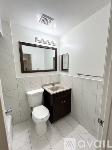 A bathroom with a toilet, sink and mirror.
