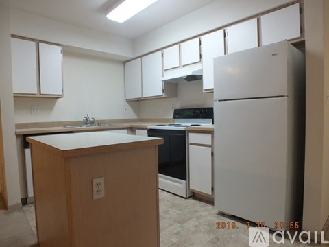 A kitchen with white appliances and wooden cabinets.