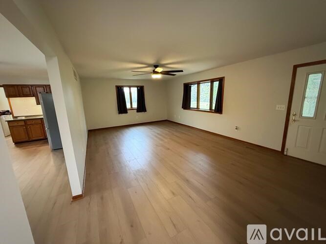 A spacious room with wooden flooring and a ceiling fan.