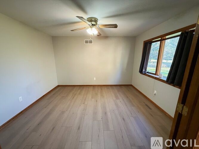 Empty room with wooden floor and ceiling fan.