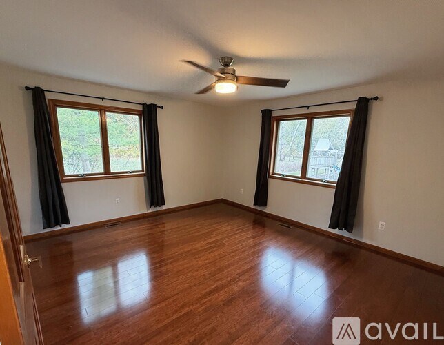 A room with wooden flooring and a ceiling fan.