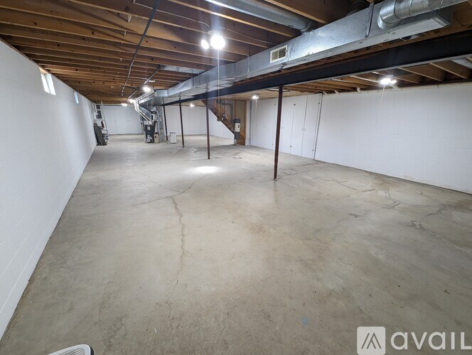 A large empty room with a wooden ceiling and a staircase in the background.