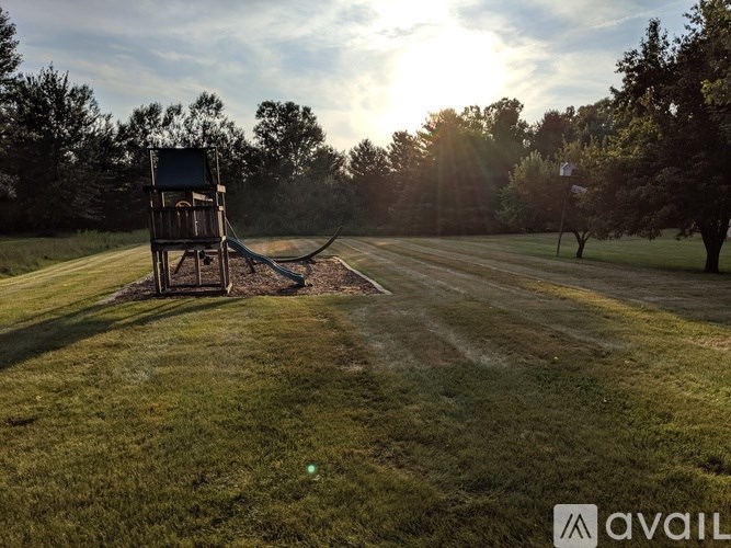 A sunny day at the park with a swing set and a tree.