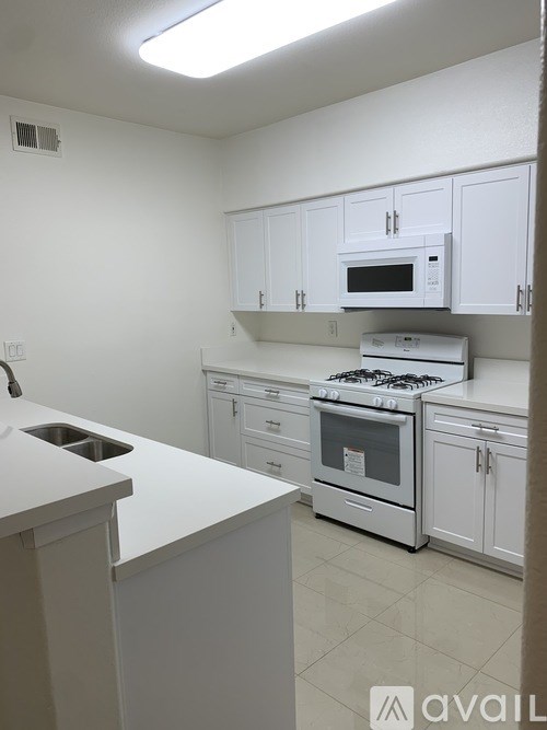 A kitchen with white cabinets and appliances.
