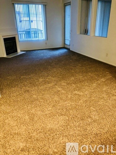 A room with a carpeted floor and a window with blinds.