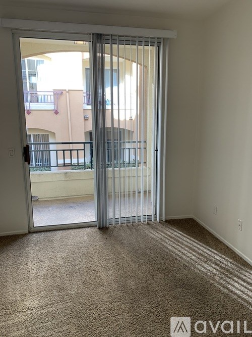A room with a carpeted floor and a sliding glass door leading to a balcony.