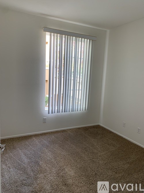 A room with a carpeted floor and a window with blinds.