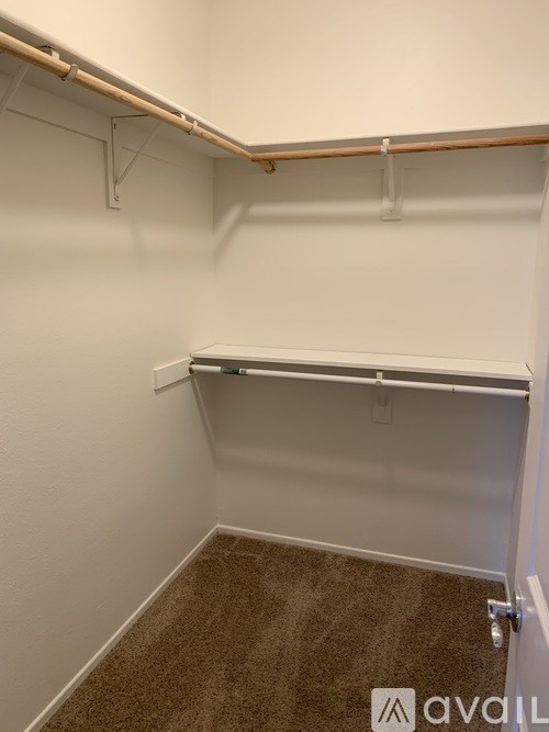 A white wall with a shelf and a brown carpet.