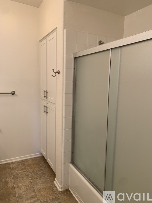 A white bathroom with a glass shower door and a tiled floor.