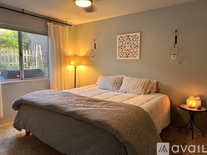 A bedroom with a large bed and a window overlooking a backyard.