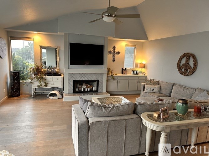 A living room with a grey couch and a fireplace.