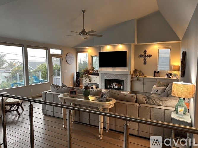 A living room with a television, a fireplace, and a glass railing.
