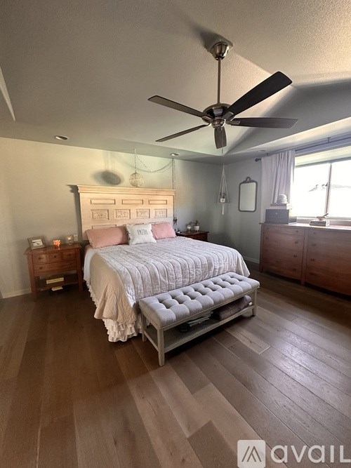 A bedroom with a bed, dresser, and ceiling fan.