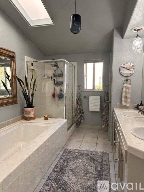 A bathroom with a white bathtub and a patterned rug.