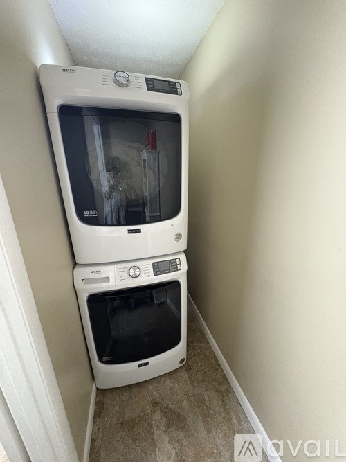 A small white washing machine and dryer stacked on top of each other in a narrow space.
