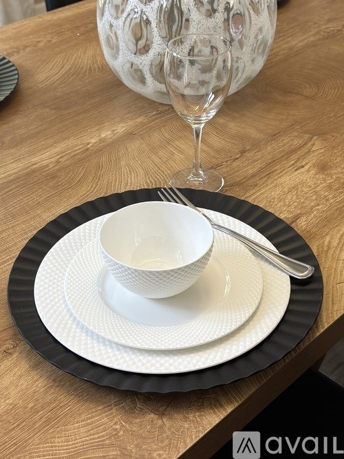 A white bowl sits on a black and white plate with a fork on the side.