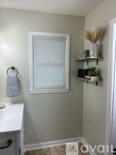 A bathroom with a white sink and a window with blinds.