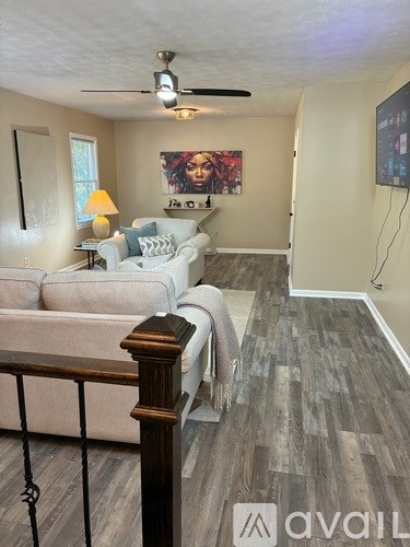 A living room with a white couch and a painting on the wall.