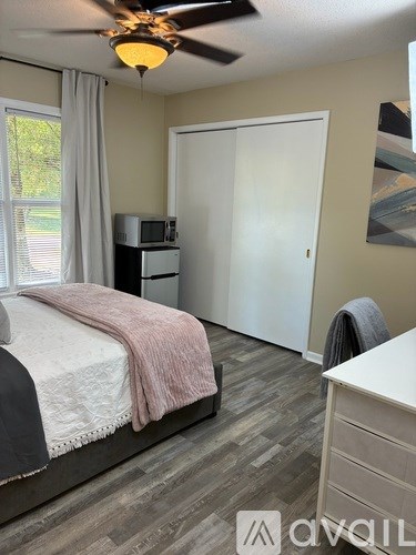 A bedroom with a bed, dresser, and a ceiling fan.