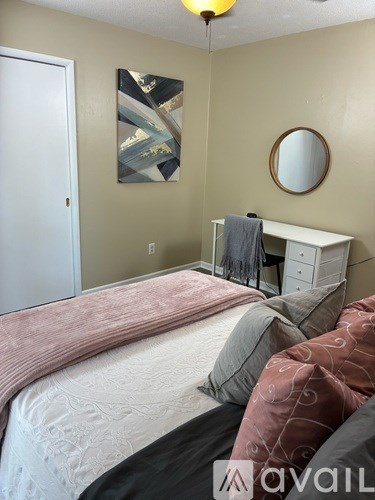 A bedroom with a bed, dresser, mirror, and artwork.