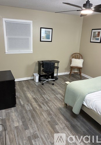 A room with a bed, chair, and a fan.