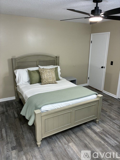 A bedroom with a bed, pillows, and a ceiling fan.