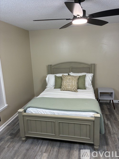 A bedroom with a bed, pillows, and a ceiling fan.