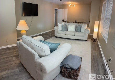 A living room with a white couch and a flat screen TV mounted on the wall.