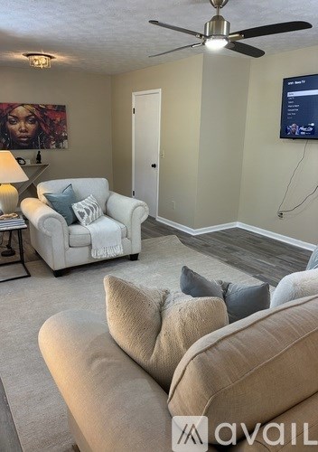 A living room with a white couch and a television mounted on the wall.
