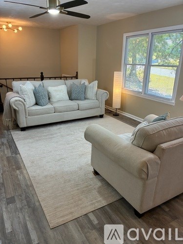 A living room with a white couch and a beige chair.