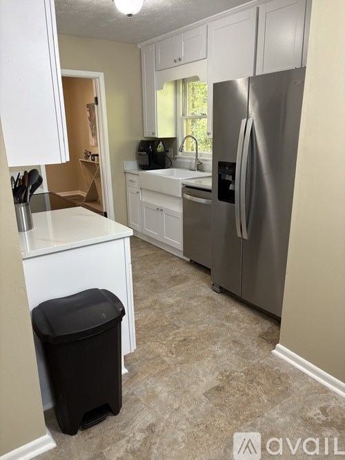 A kitchen with a black trash can and a silver refrigerator.