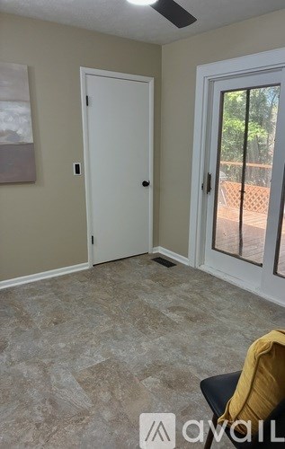 A room with a white door and a window with a view of a fence.