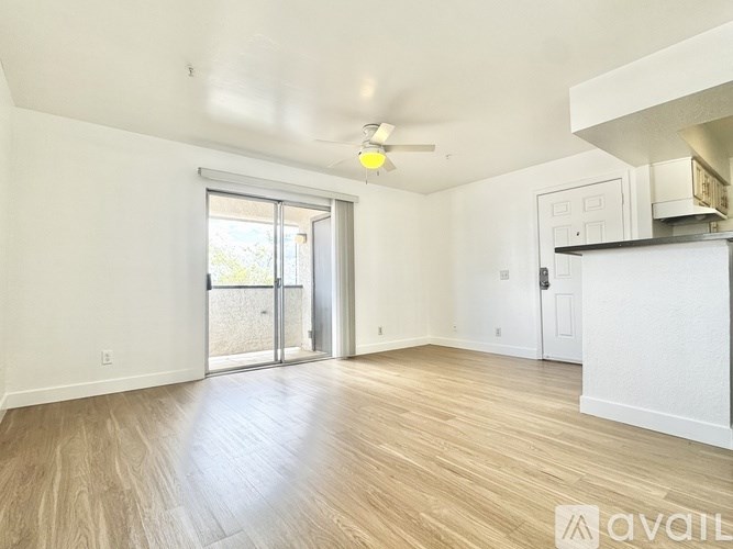 A spacious living room with a sliding glass door leading to a balcony.
