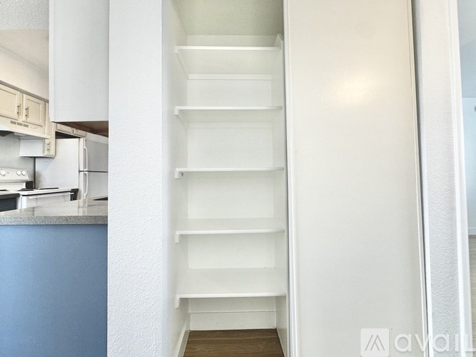 A kitchen with a blue counter and white shelves.