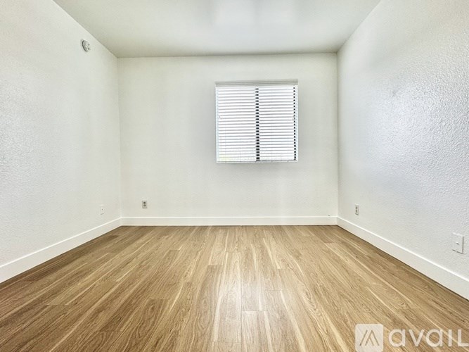 A room with wooden flooring and a window with blinds.