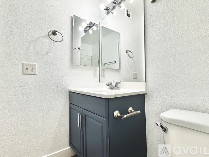 A bathroom with a white tub, a sink with a mirror above it and a cabinet below it.