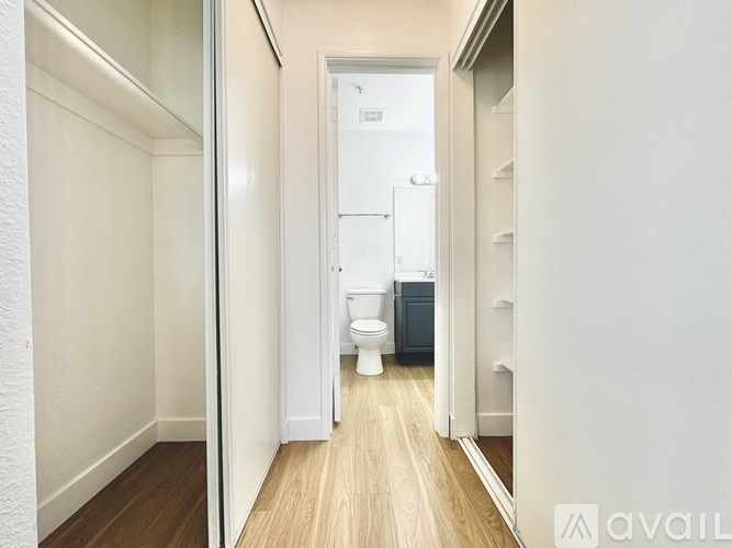 A bathroom with a toilet and sink in a narrow hallway.