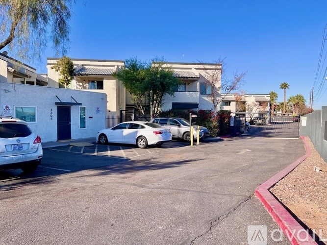 A white car is parked in a parking lot with other cars and buildings in the background.