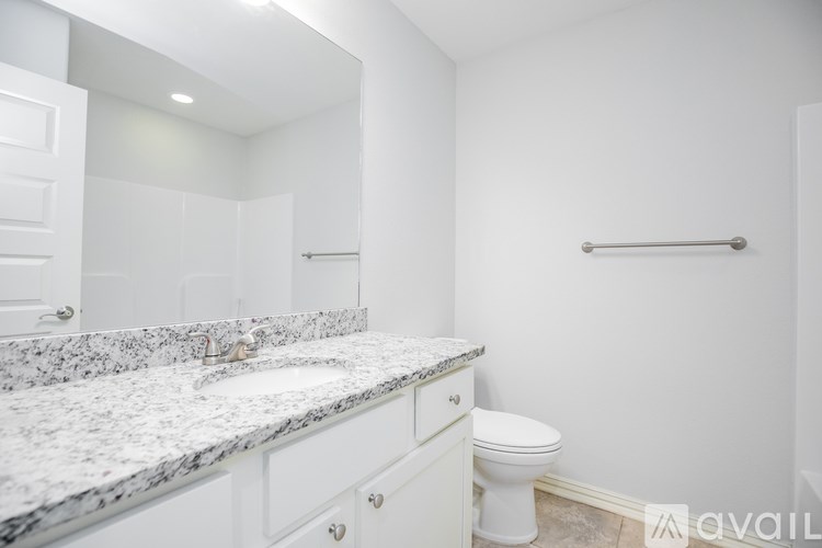A bathroom with a marble countertop and white fixtures.