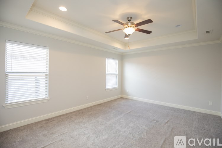 A room with a ceiling fan and two windows.
