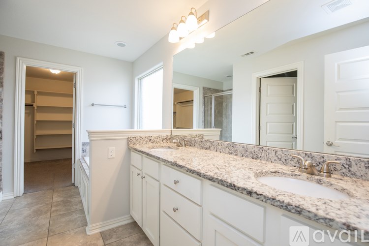 A bathroom with a marble countertop and white cabinets.