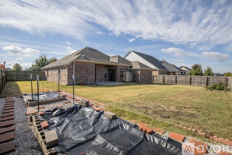 A backyard with a black tarp covering the ground.