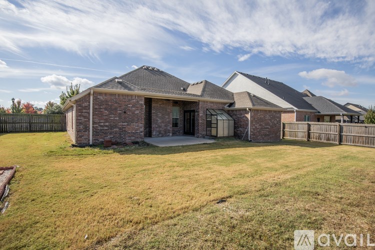 A house with a brick exterior and a covered patio is surrounded by a grassy lawn.