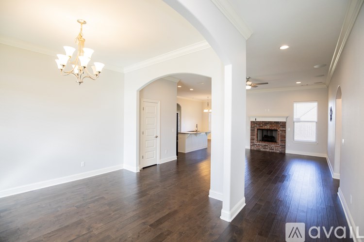 A large, empty room with wood floors and a chandelier.