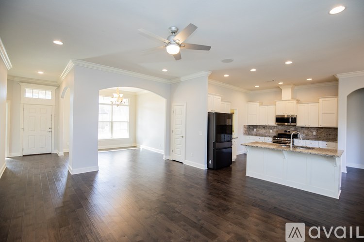 A spacious living room with a kitchen in the background.