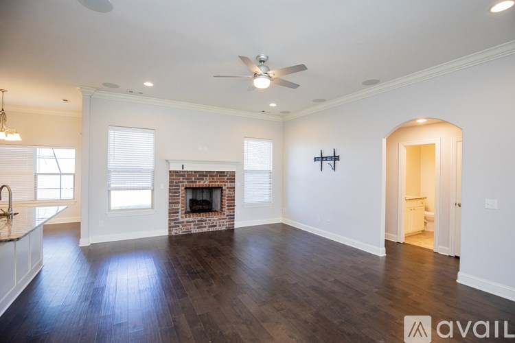 A spacious living room with a fireplace and a ceiling fan.