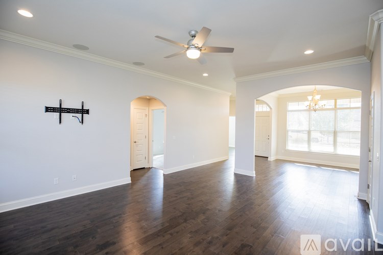 A spacious room with wooden floors and a ceiling fan.