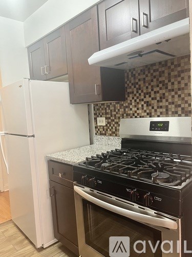 A kitchen with a white refrigerator, black stove, and brown cabinets.