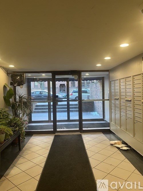 A hallway with a black mat on the floor leading to a glass door.